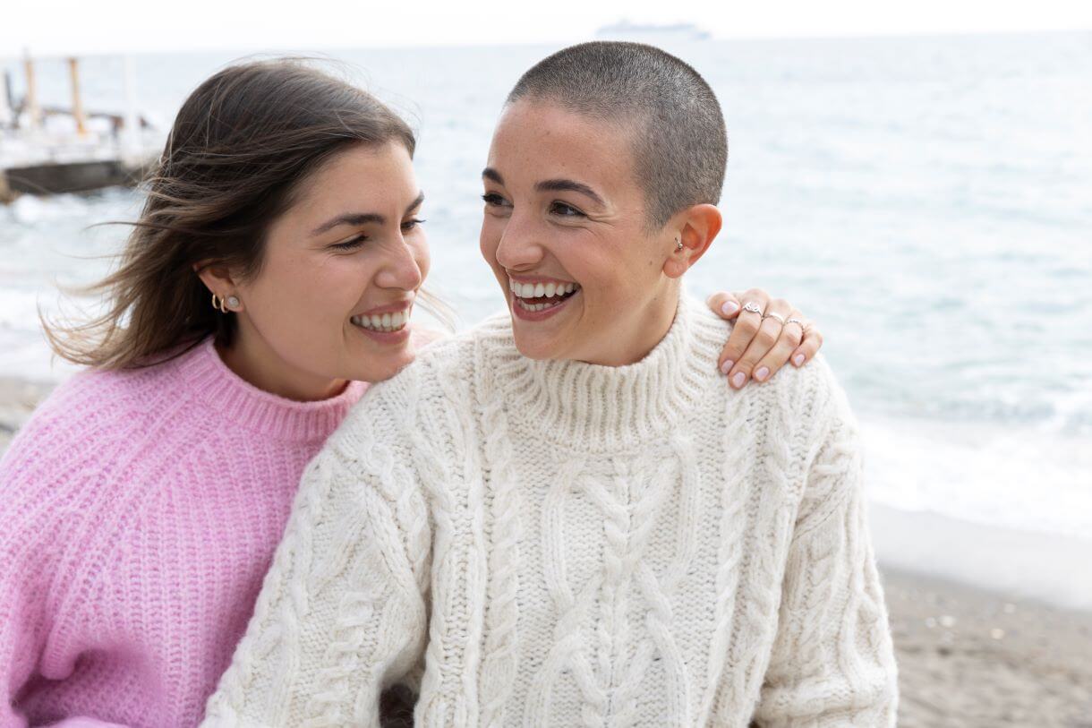 mulher careca feliz com autoestima elevada passeando com uma amiga na praia.