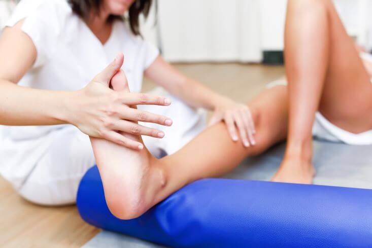 fisioterapeuta manipulando perna de paciente.