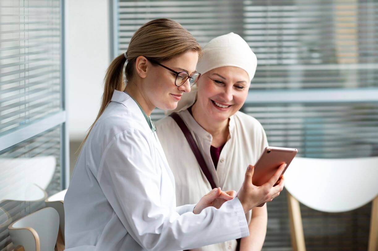 médica e paciente oncológica olhando para tablet.
