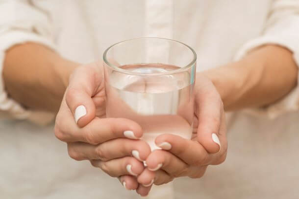 mulher segurando copo de água efeitos colaterais tratamento de câncer.