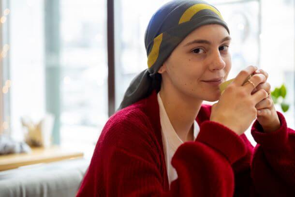 mulher usando lenço na cabeça tomando um chá.